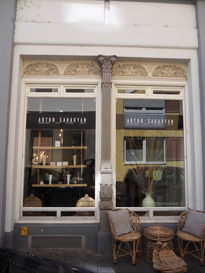 Altbaufassade mit den Schaufenstern des Salons und Korbstühlen davor