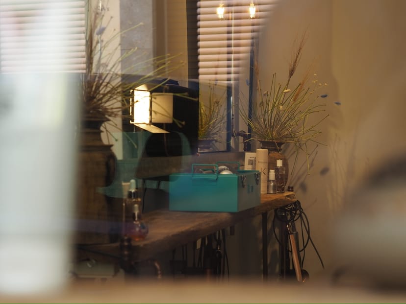 Arbeitsplatz mit Lampe, Trockenblumen und türkisfarbenem Koffer