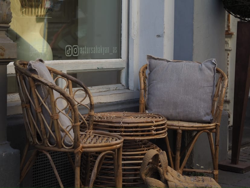 Korbstühle und Tisch vor dem Schaufenster des Salons
