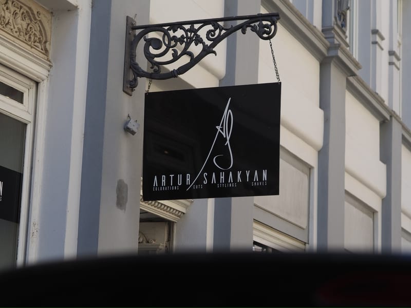 Ausleger-Schild mit dem Artur-Sahakyan-Logo an der Hausfassade