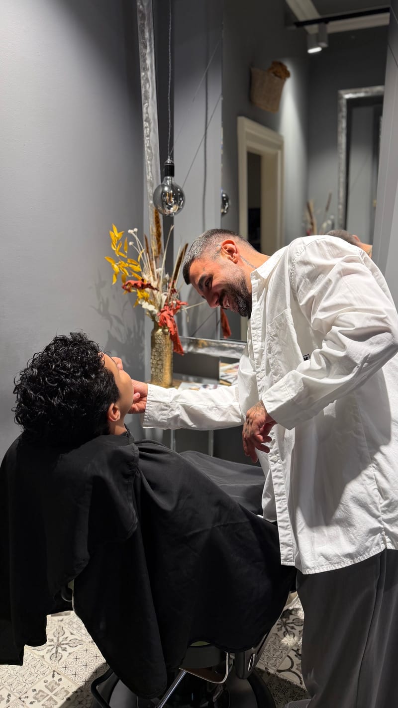 Artur Sahakyan lacht bei der Arbeit mit einem Kunden mit lockigem Haar